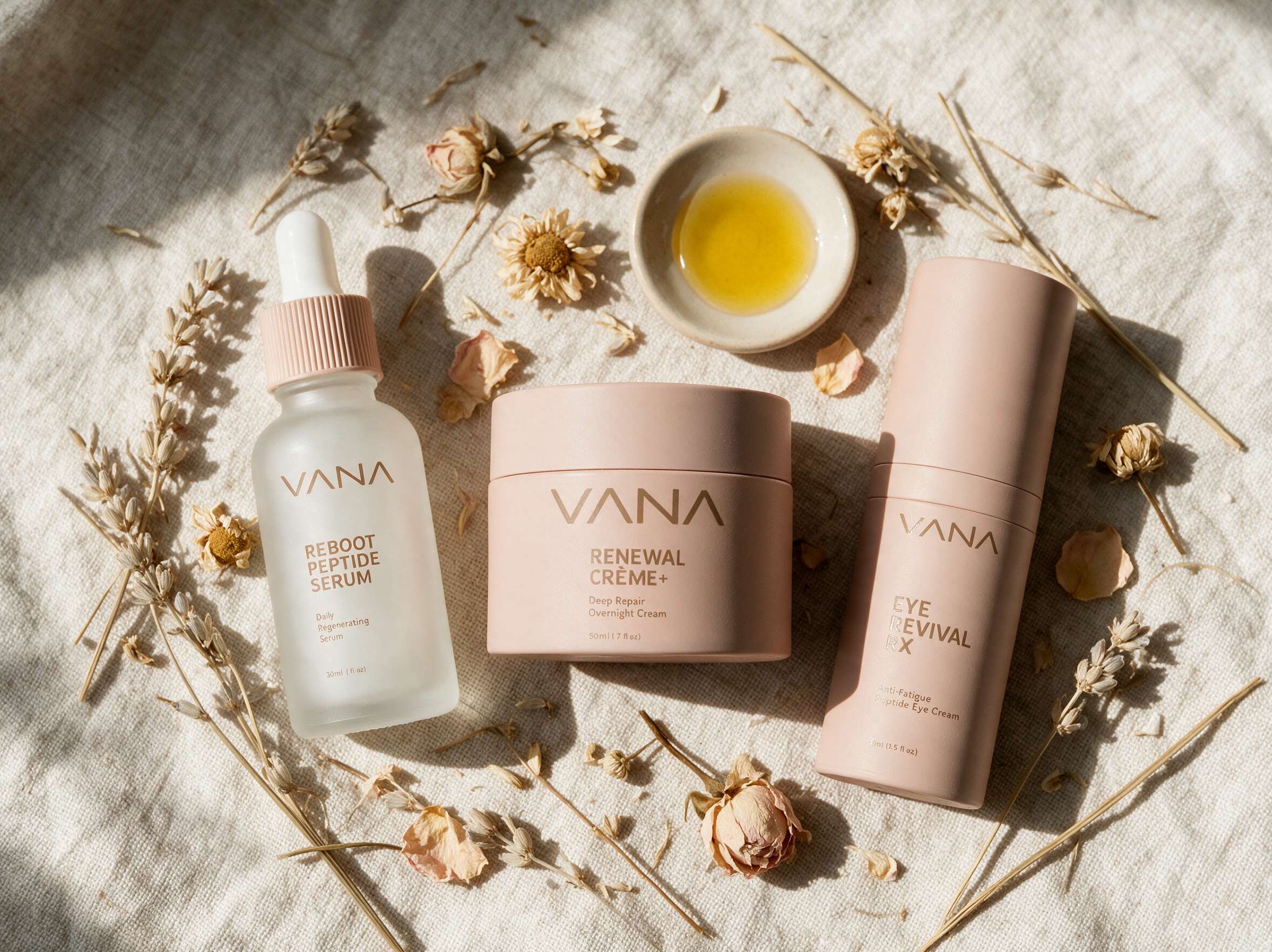 VANA serum, creme, and eye cream arranged with dried flowers on linen